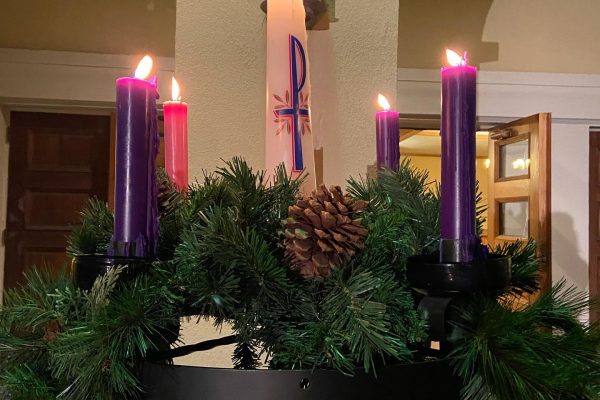 FCC Pomona's evergreen Advent wreath with all four candles lit, plus the Christ candle.